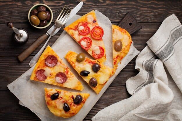 Pieces of different greek pizzas with olives, italian margarita and pepperoni on a dark wooden rustic. 